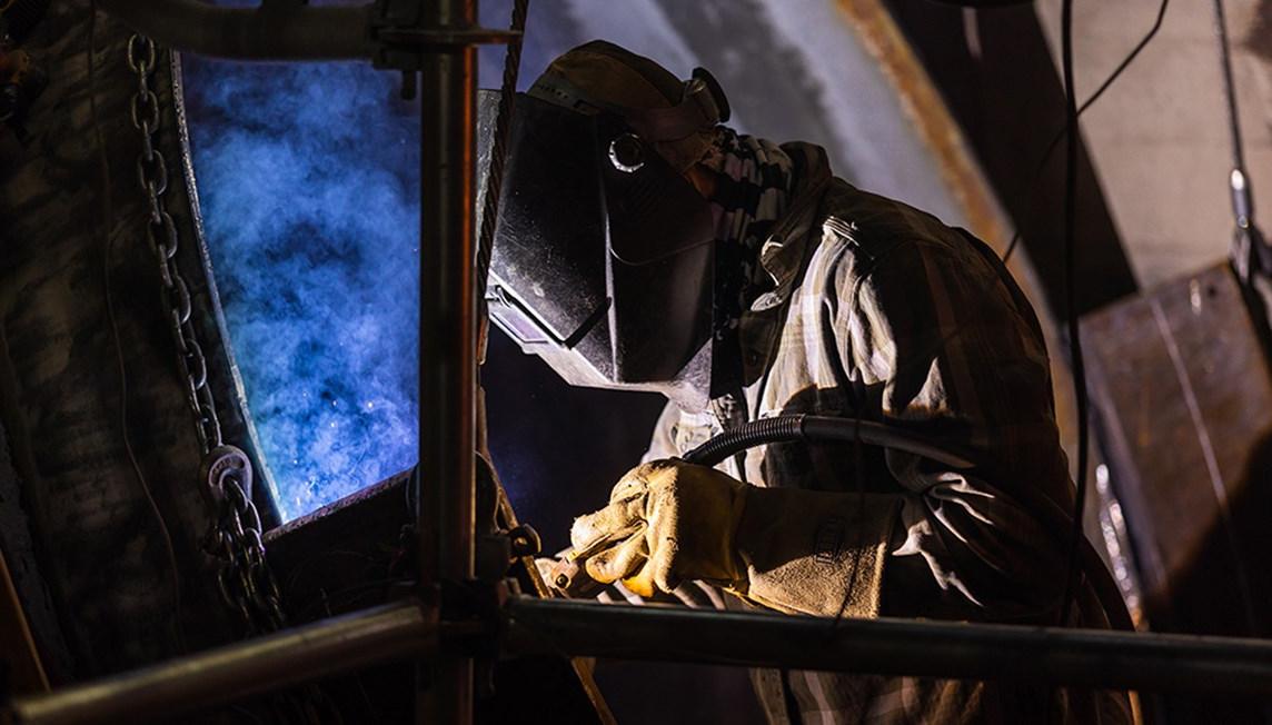 A welder attaching metal sheets to a frame